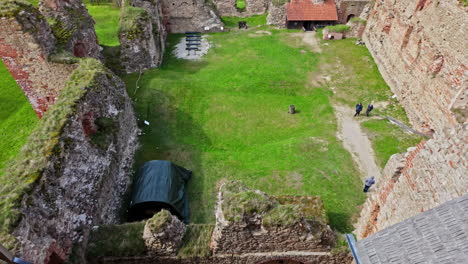 vista de las ruinas del castillo de bauska en letonia con césped verde y algunas personas explorando