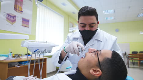 Arab students practicing in dentistry. One male student applies electric dental tool to another one. Close up.