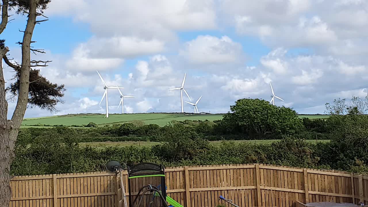 Onshore wind turbines at a wind farm on rolling downs generating green electricity power