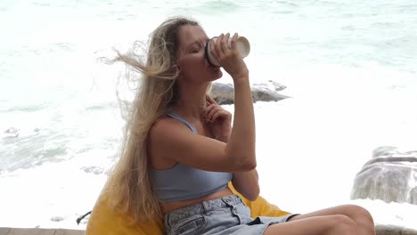 mujer disfrutando de café junto al océano