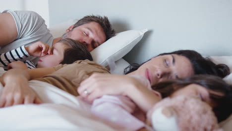 peaceful parents with children sleeping in bed together