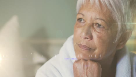 Animation-of-glowing-lights-over-thoughtful-senior-woman-in-background