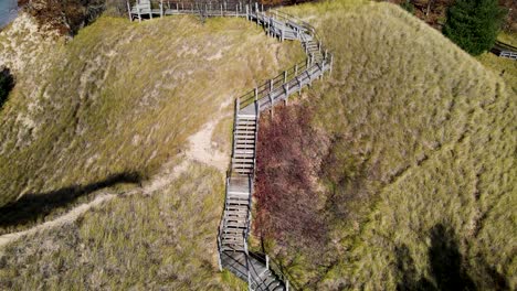 aerial rise and revere tracking motion over a sand dune and boardwalk