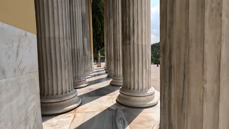 walking through pillars of a greek building.