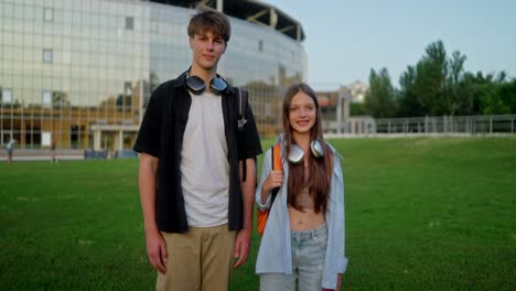 two teenagers smiling at the camera outside of a school