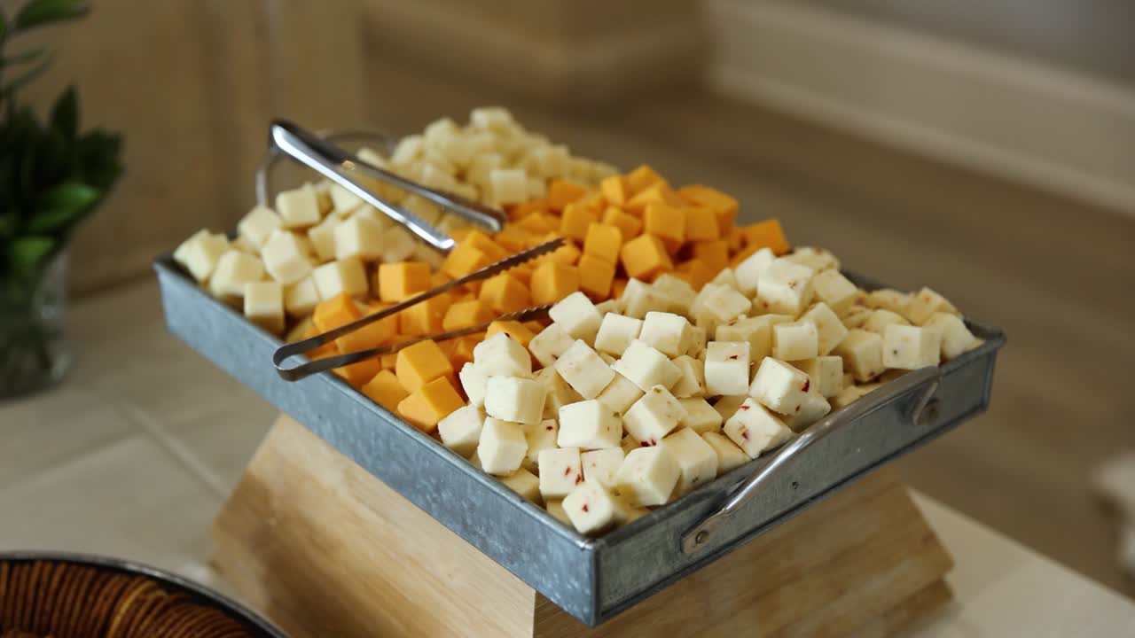 Cubetti di formaggio Cheddar stagionato, Americano e Svizzero su tagliere di salumi e formaggi.