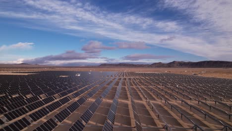 aerial drone footage of solar panel field in joshua tree national park on a sunny day with mountains in the background, moving forward