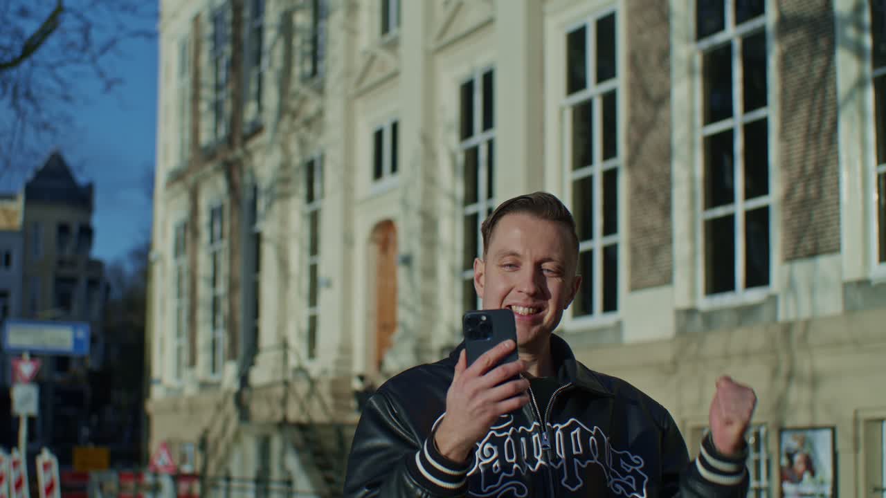 A white Caucasian male man model actor with cellphone expresses emotional happiness and winner's mood