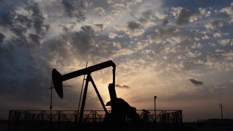 silhouette of crude oil pump standing still  in the oilfield at cloudy sunset