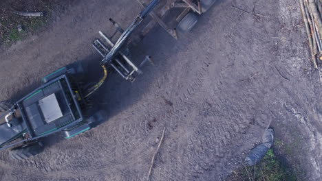 vista aérea de arriba hacia abajo de un tractor y un remolque de registro que conducen a través del marco
