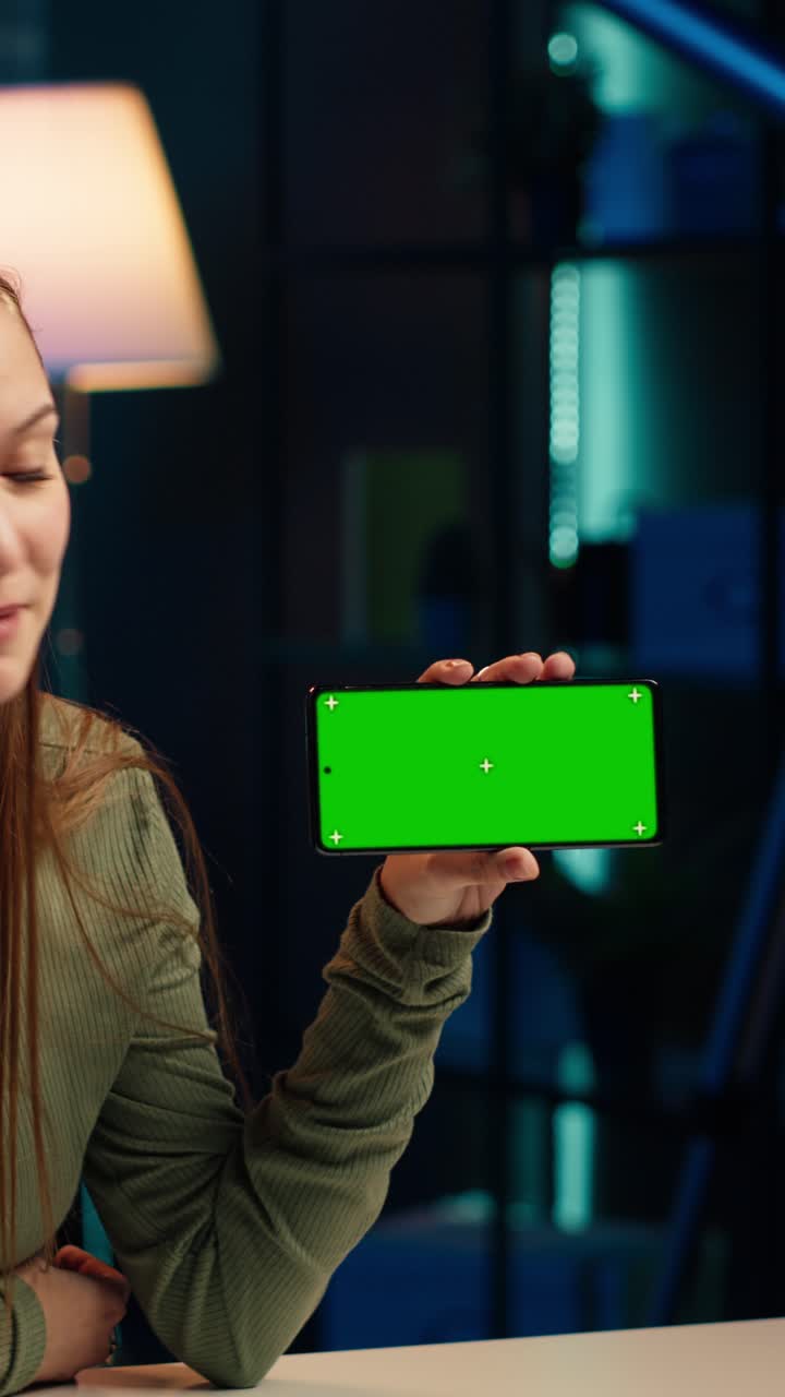 Donna sorridente che tiene in mano uno smartphone con schermo verde orizzontale