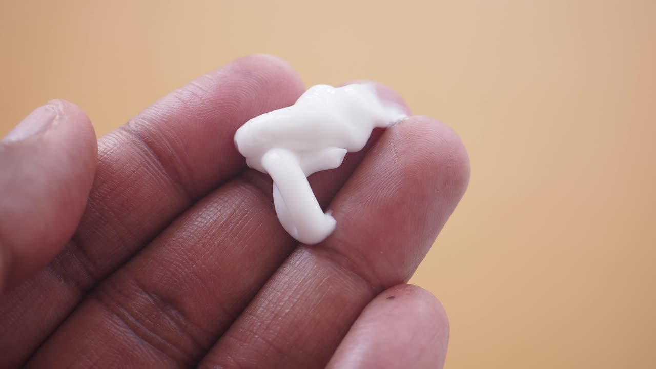 Close-up of a hand holding a dollop of white cream