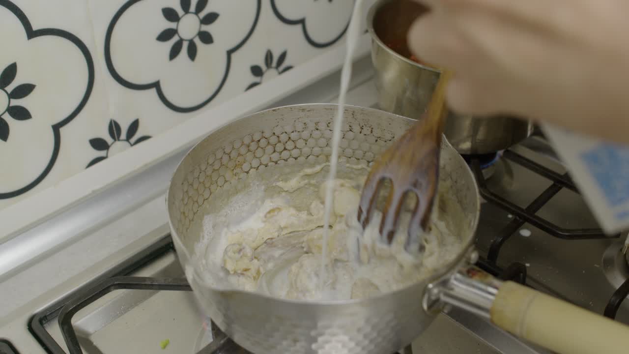 agregar leche y mezclar salsa de champiñones con una cuchara de madera en una olla