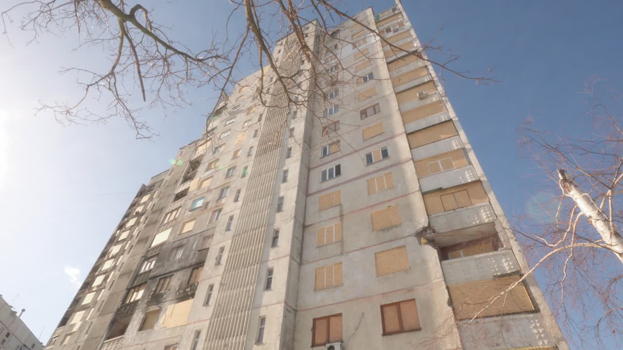 Tall Residential Building with Boarded Windows in Ukraine After Russian Invasion in tilt up shot
