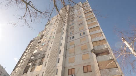 tall residential building with boarded windows in ukraine after russian invasion in tilt up shot