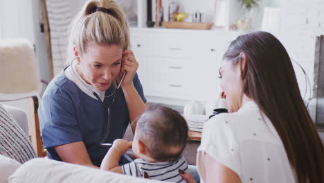 female healthcare worker visiting young mum and her infant son at home, using stethoscope, close up