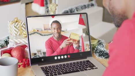 hombre afroamericano con decoraciones de navidad haciendo una llamada de video con hombre afroamericano