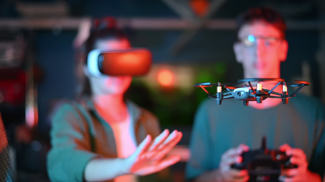 Teens doing experiments in robotics in a laboratory. Boy with controller and girl in VR headset controlling a flying drone using her hand. Red and blue illumination. Slow motion