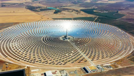 large circular power plant of solar panels in spain. there is the reflection of the sun in the the panels which produce renewable energy, solar energy - aerial view with a drone - environment concept