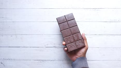 top view of holding a dark chocolate on white wooden table