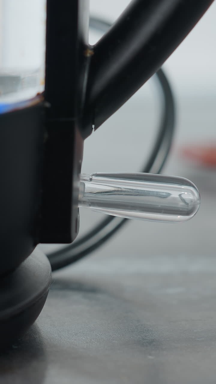 Close-up of individual turning on electric water boiler with blue light blinking, showing water level inside, the kettle is powered and heating water in kitchen environment