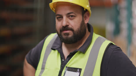 caucasian male factory worker at a factory  wearing a high vis vest and a hard hat standing