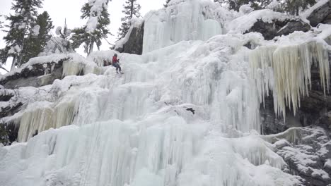 Mann-Wehrt-Sich-Auf-Einem-Großen-Gefrorenen-Wasserfall-Ab-–-Eisklettern-–-Standbild