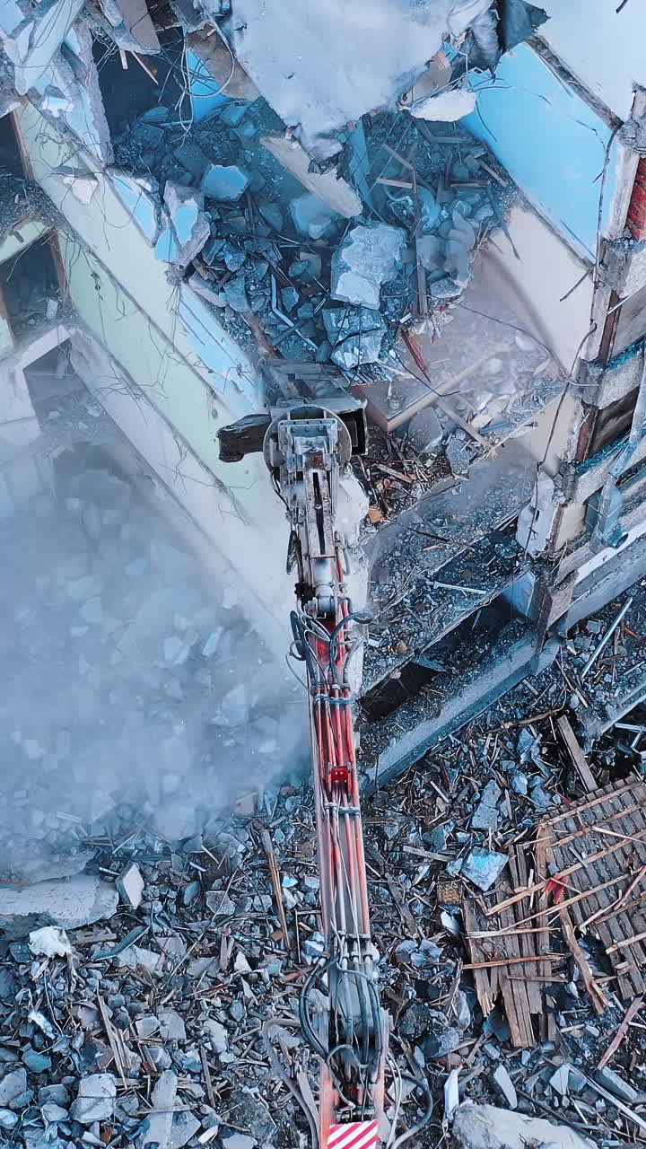 Demolishing machinery breaks the floors and walls of the ruin. Debris falling down with heavy dusty clouds. Rising over the ruins and debris. Vertical video
