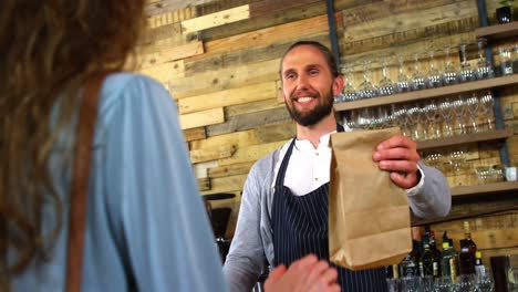 waiter giving parcel to female costumer at counter