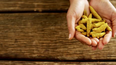 hands holding turmeric against wooden table 4k