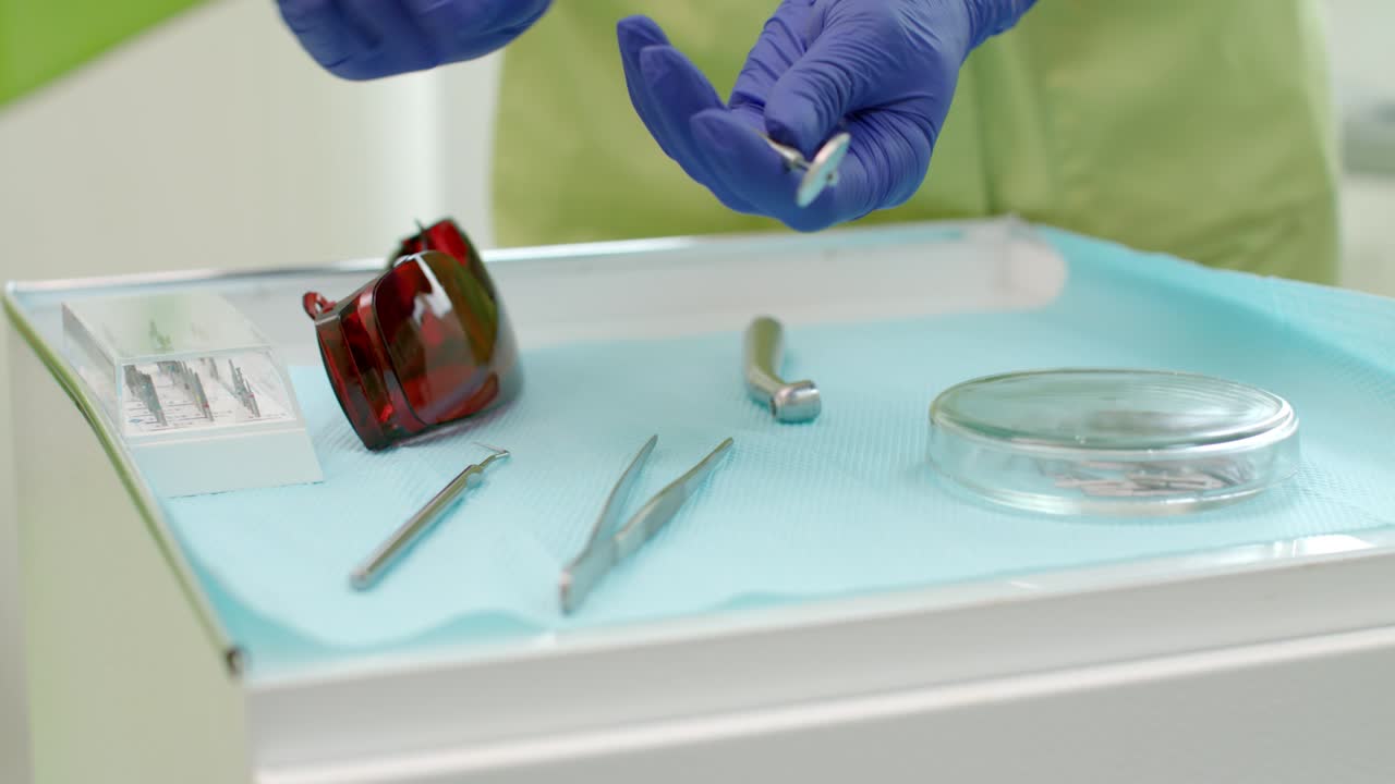 manos del dentista tomando herramientas de odontología de la mesa. estomatólogo tomando el espejo dental