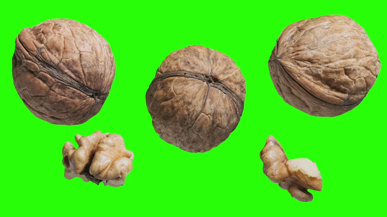 Tre noci e due noci sgusciate ruotano lentamente su uno sfondo nero
