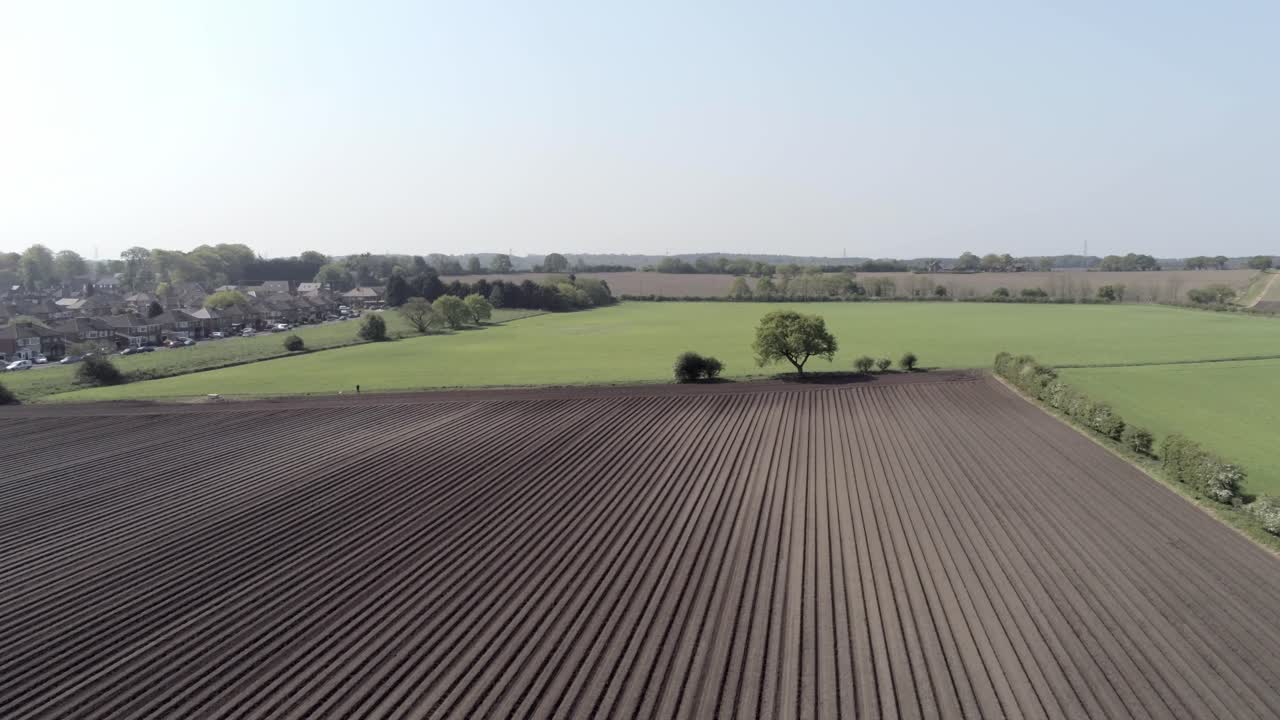 Drohnen-Luftaufnahme: Reihen von fruchtbarem britischem Ackerland mit Furchen in der Landschaft, langsames Heranfahren.