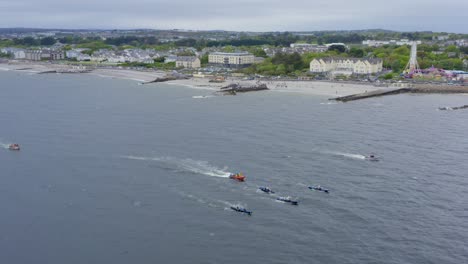 vista lateral aérea orbital y seguimiento de barcos de remos de currach que corren a través de la bahía abierta de galway, irlanda