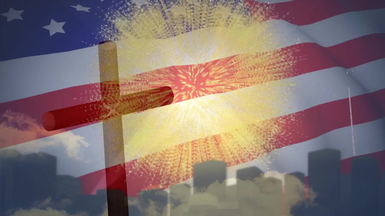 Piccolo punto luminoso che innesca fuochi d'artificio che esplodono sopra una bandiera attorno a una croce, celebrando il patriottismo.