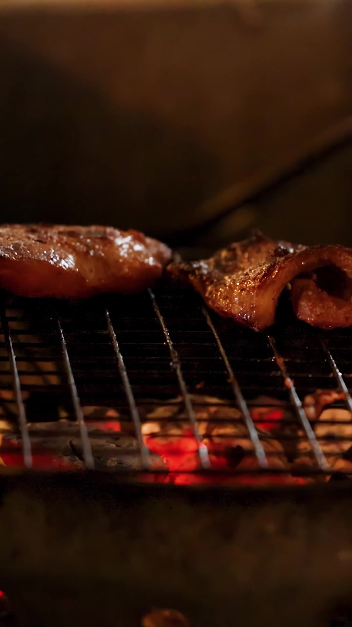 Primo piano di carne di maiale marinata che sfrigola su braci ardenti di carbone in un mercato all'aperto