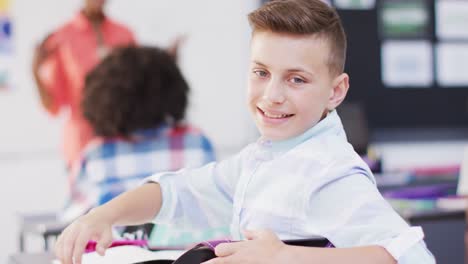 Portrait-of-diverse-female-teacher-and-happy-schoolchildren-at-desks-in-school-classroom