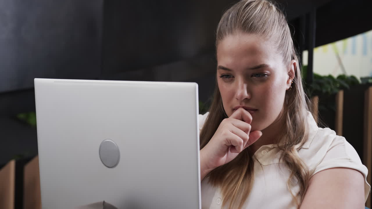 Working on laptop, woman in office thinking and focusing on task