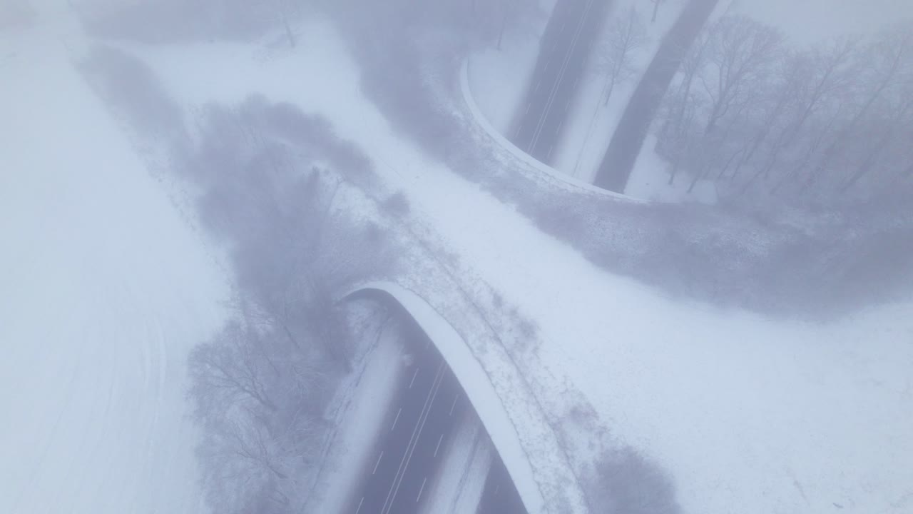 Aerial fixed frame of contrasting Dutch snow landscape with environment nature reserve infrastructure ecoduct in hazy winter conditions