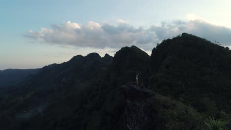 Mujer-Con-Las-Manos-En-El-Aire-Despreocupada-Viendo-La-Puesta-De-Sol-Desde-El-Pico-Kandungaw,-Antena