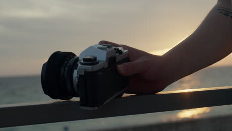 professional freelancer photographer holding vintage camera with lenses at sunset on the ocean sea