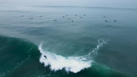 aerial view of an unrecognizable surfer dropping into a barreling wave in carlsbad california