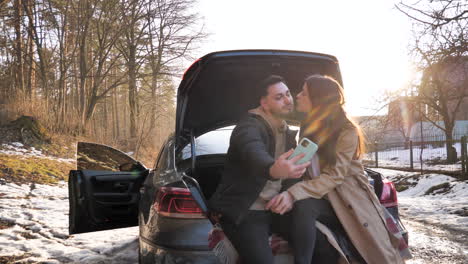 pareja caucásica tomando selfies en un bosque nevado.