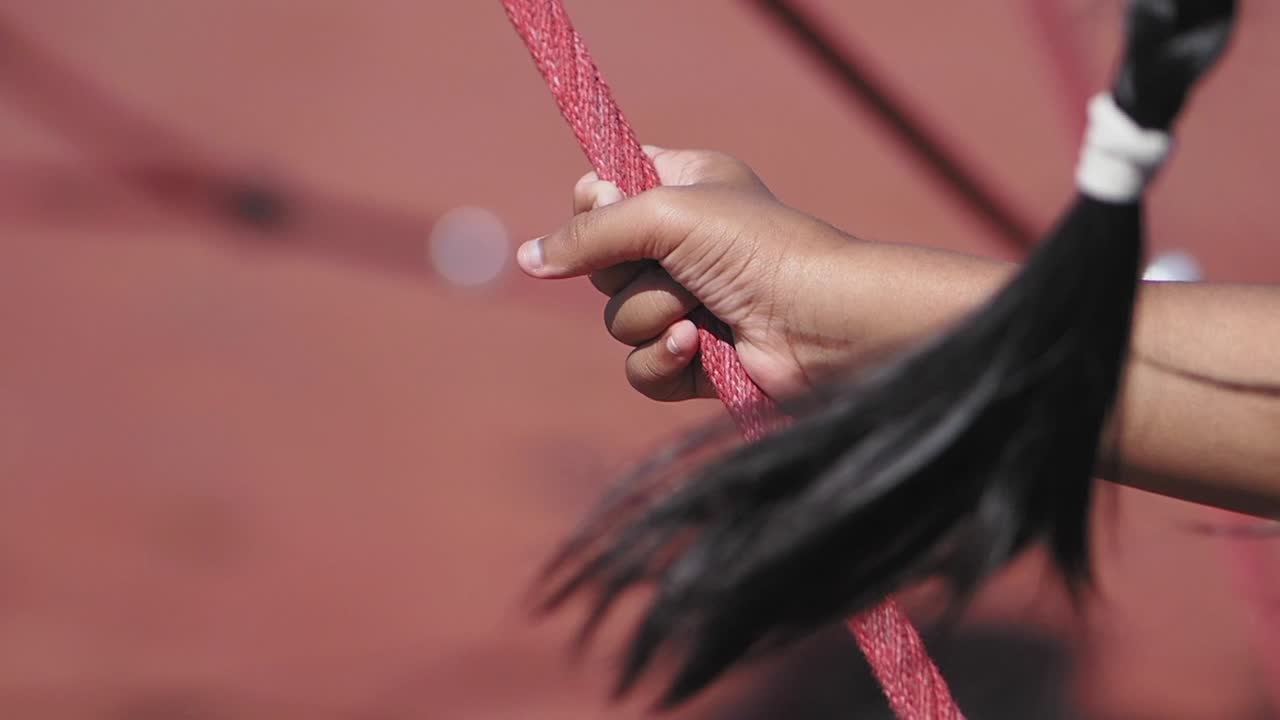Hand holding a red rope with a braid nearby