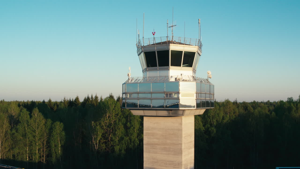 Aerial shot of air traffic control tower in green forest with clear skies