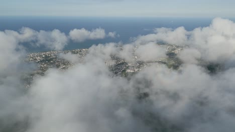 aerial: drone shot showing the city of peurto plata behind the clouds