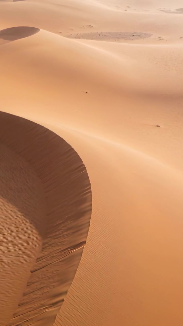 Video verticale: Telecamera panoramica che inizia la discesa sulle dune, mostrando il bordo a mezzaluna, le increspature e le rocce.