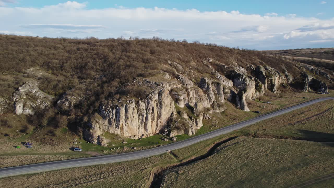 una vista aérea panorámica de una carretera sinuosa al lado de acantilados rocosos y llanuras cubiertas de hierba en las gargantas de dobrogea
