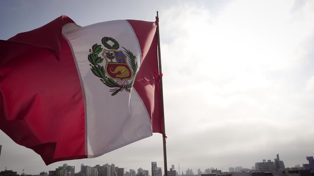 cámara lenta: bandera del perú ondeando en el viento sobre el paisaje urbano de lima