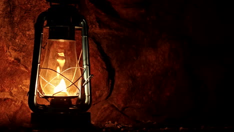 metal oil paraffin lantern lighting up a rock wall, providing a warm glow at night, an antique ambiance with timeless charm